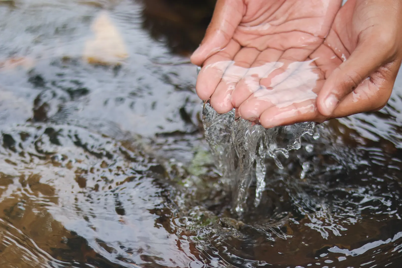 Manos en agua limpia de río — sostenibilidad de recursos hídricos