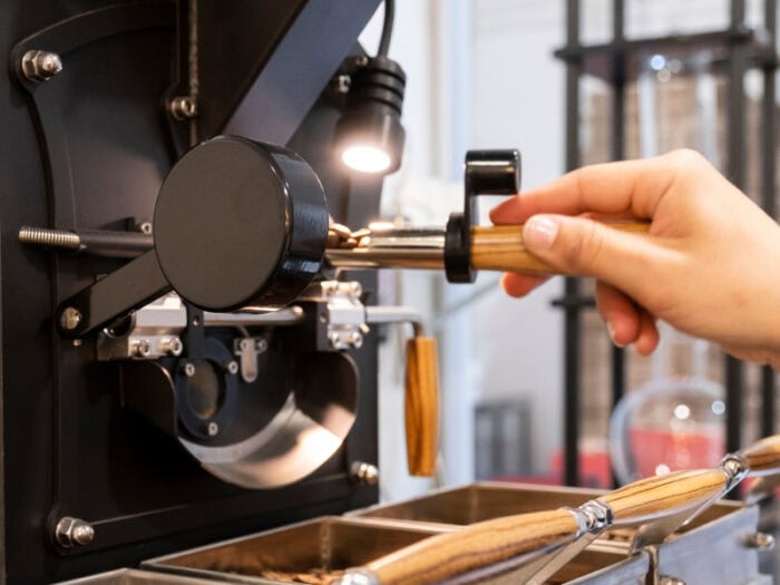 Café Raizal, café natural de origen colombiano, moliendo café con maquinaria profesional en una cafetería moderna.