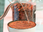 Cafes raizal, café colombiano de origen natural preparado en una taza con agua caliente, café en grano en una jarra cerca, café de calidad para los amantes del café colombiano auténtico y de origen bajo método natural.