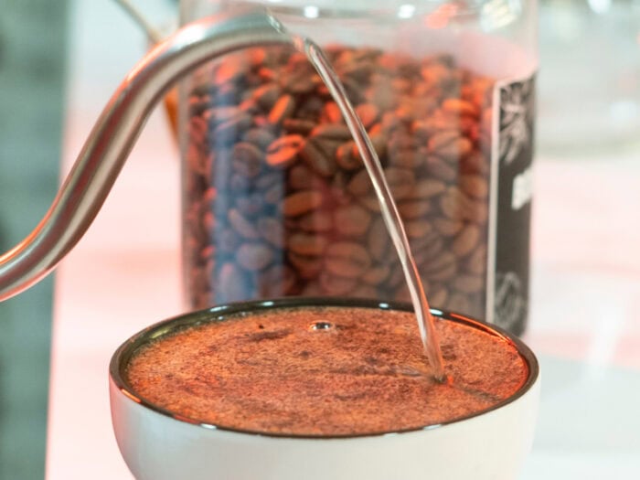 Cafes raizal, café colombiano de origen natural preparado en una taza con agua caliente, café en grano en una jarra cerca, café de calidad para los amantes del café colombiano auténtico y de origen bajo método natural.